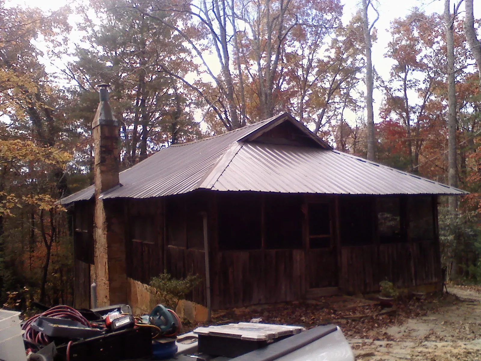 Brown metal hip roof on an old cabin with a stone chimney in Buford