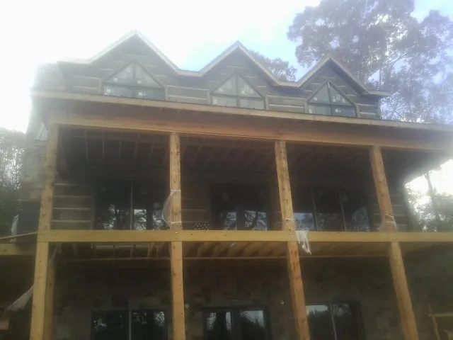 Dormers and porch framing on a large log home under construction — Roof Coating work by our crew in Buford