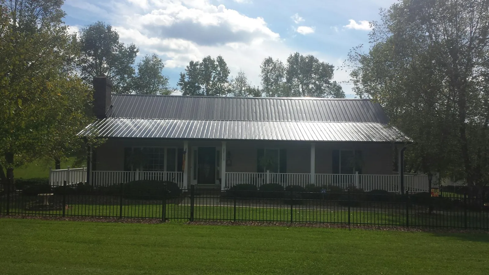 Gray metal roof on a brick ranch with a full width front porch — Gutter Guard Installation work by our crew in Buford