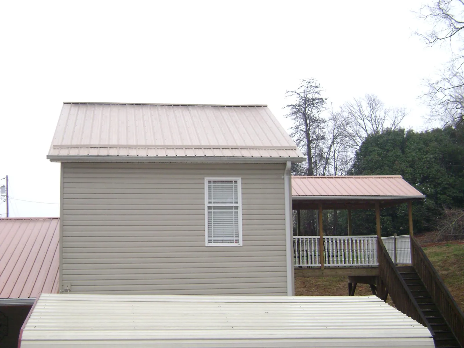 Tan metal roofs on a two story addition and attached porch, from a Roof Replacement job in Buford